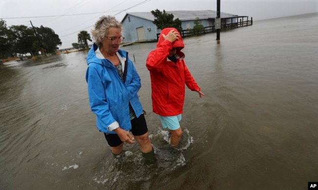 Dos residentes de St. Mary, en Georgia, caminan cerca de sus casas el 4 de septiembre de 2019, luego del paso del huracán Dorian. Curtis Compton/Atlanta Journal-Constitution via AP.