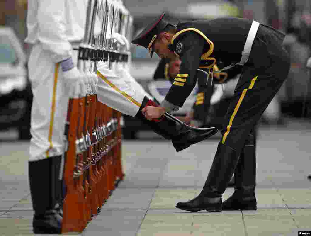 A members of the honour guard cleans the boots of fellow guards ahead of a welcoming ceremony for the visiting Portugal's President Anibal Cavaco Silva (not seen), outside the Great Hall of the People in Beijing.