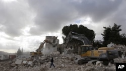 A worker walks past excavators during the demolition of the Shepherd Hotel in the Sheikh Jarrah neighbourhood of East Jerusalem, 09 Jan 2011.