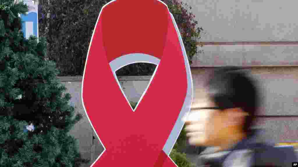 La silouhette d&#39;un homme qui passe près du ruban rouge, symbole international de sensibilisation au sida à Séoul, Corée du Sud, 1er décembre 2015.&nbsp;