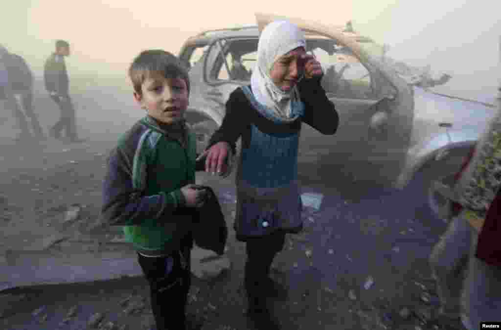 A girl and boy are shaken as they stand near a site hit by what activists said were barrel bombs dropped by government forces in Aleppo, Syria, Jan. 29, 2014.&nbsp;