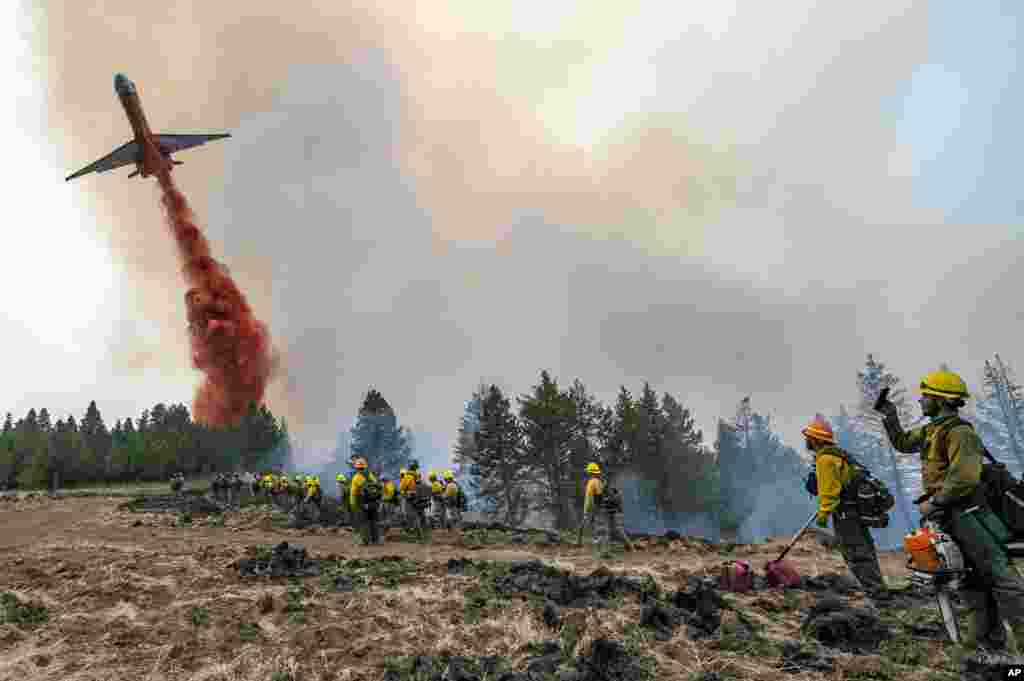 Wildland firefighters watch and take video with their cellphones as a plane drops fire retardant on Harlow Ridge above the Lick Creek Fire, southwest of Asotin, Washington, July 12, 2021.