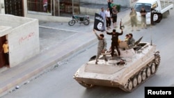 FILE - Militant Islamist fighters hold the flag of the Islamic State group while taking part in a military parade along the streets of northern Raqqa province, Syria, June 30, 2014.