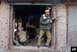 Indian paramilitary soldiers take position in a shop during a gun battle with suspected militants in Srinagar, India, Nov. 23, 2005.