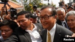 Pemimpin oposisi Kamboja, Sam Rainsy (kanan), tiba di pengadilan kota Phnom Penh (14/1).