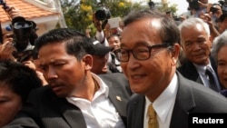 Sam Rainsy (R), leader of the opposition Cambodia National Rescue Party (CNRP), arrives at the Municipal Court in central Phnom Penh, Jan. 14, 2014. 