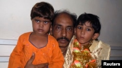 Seven-year-old groom Mohammad Waseem (R) sits with his four-year-old bride Nisha (L) and his father Mohammad Ismil in a police station in Karachi October 31, 2008. Pakistani police raided a child marriage ceremony in the city of Karachi and arrested a cle