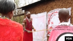 Trachoma monitor Lester Mortai teaches a group women how to prevent trachoma at household level, Kajiado, Kenya. (Mohammed Yusuf for VOA)