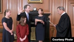 Chief Justice John Roberts administers the constitutional oath to Brett Kavanaugh at the Supreme Court building in Washington, Oct. 6, 2018, with the new justice's wife, Ashley, holding the Bible and their daughers looking on. (F. Schilling/Collection of the Supreme Court of the United States)