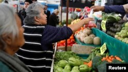 A woman buys tomatoes in a groceries stall at Granada market in Mexico City, Mexico, Jan. 10, 2017. 