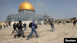 Pripadnik izraelske policije trči za snimateljem tijekom sukoba s Palestincima u kompleksu u kojem se nalazi džamija Al-Aqsa, koja je muslimanima poznata kao Plemenito utočište, a Židovima kao Hramska planina, u starom gradu Jeruzalema, 10. maja 2021. REUTERS / Ammar Awad