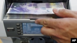 A bank clerk places1000 Swiss franc banknotes in a money counter in a Bank in Bern (file photo)