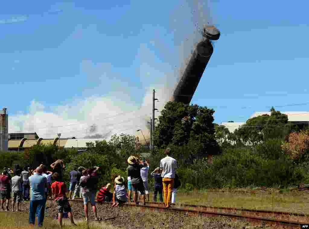 A 200-meter-high chimney, built from about 7,000 tonnes of concrete, bricks and steel, is brought down in a controlled explosion at Port Kembla, south of Sydney, Australia. Nearly 1,000 explosives charges were placed around the copper stack, which broke into at least two pieces just before hitting the ground as thousands of people gathered to watch the explosion.