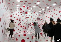 People view a polka-dotted room created by Japanese artist Yayoi Kusama, part of the exhibit, "Yayoi Kusama: Festival of Life," on display at the David Zwirner gallery in the Chelsea section of New York, Nov. 21, 2017.