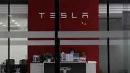 Seorang resepsionis tampak bekerja di showroom Tesla di Beijing, China, pada 4 Januari 2022. (Foto: AP/Ng Han Guan)