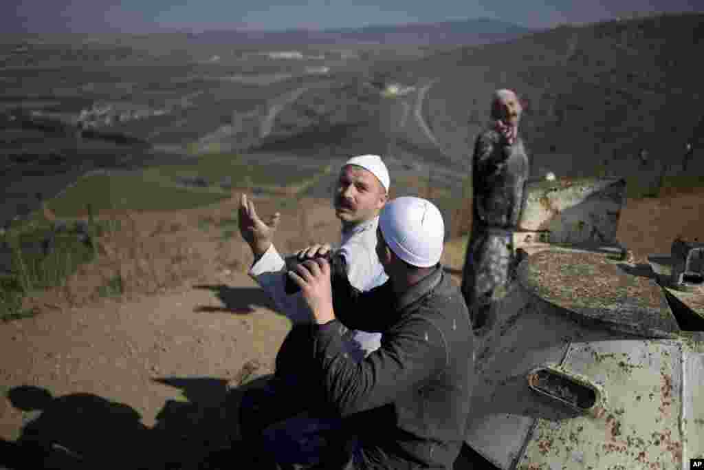 Pria-pria dari komunitas agama Druze melihat dari daerah Dataran Tinggi Golan yang dikuasai Israel, dekat perbatasan Israel-Suriah, saat pemberontak Suriah bentrok dengan pasukan pemerintah Presiden Bashar al-Assad (27/8).&nbsp;(AP/Ariel Schalit)