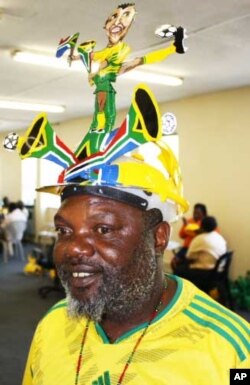 Alfred Baloyi, wearing a makarapa decorated with the image of South African football legend, Lucas Radebe, inside his factory in Johannesburg