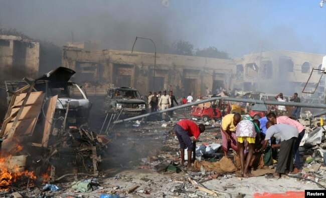 Civilians prepare to carry the dead body of an unidentified man from the scene of an explosion in KM4 street in the Hodan district of Mogadishu, Oct. 14, 2017.