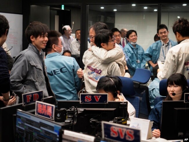 In this photo provided by the Japan Aerospace Exploration Agency, staff of the Hayabusa2 Project react as they confirm Hayabusa2 made a maneuver at the control room of the JAXA Institute of Space and Astronautical Science in Sagamihara, near Tokyo, Feb. 22, 2019.