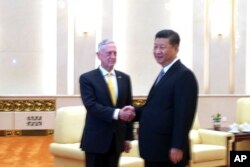 U.S. Defense Secretary Jim Mattis, left, shakes hands with Chinese President Xi Jinping as they pose for photographers before a meeting at the Great Hall of the People in Beijing, June 27, 2018.