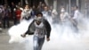 یکی از مخالفان در تلاش برای پرتاب گاز اشک آور به نقطه ای دیگر؛ گاز اشک آور توسط نیروهای امنیتی به سوی مخالفان شلیک شد.