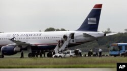 Los pasajeros de un vuelo de US Airways bajan del avión que tuvo que regresar al aeropuerto de Filadelfia, por sospechas de que había una sustancia peligrosa abordo.