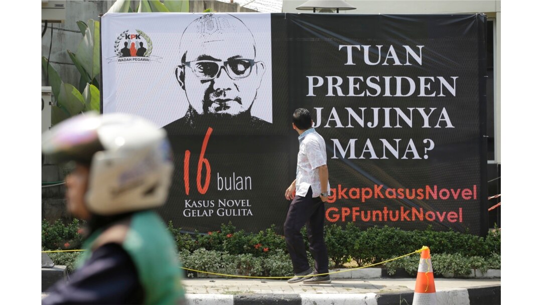 Seorang pria melihat poster di depan kantor KPK menyambut kembalinya penyidik Novel Baswedan, 27 Agustus 2018. Masyarakat mendesak Presiden Jokowi untuk membentuk tim pencari fakta dalam menyelesaikan kasus itu saat Novel kembali bekerja 16 bulan setelah
