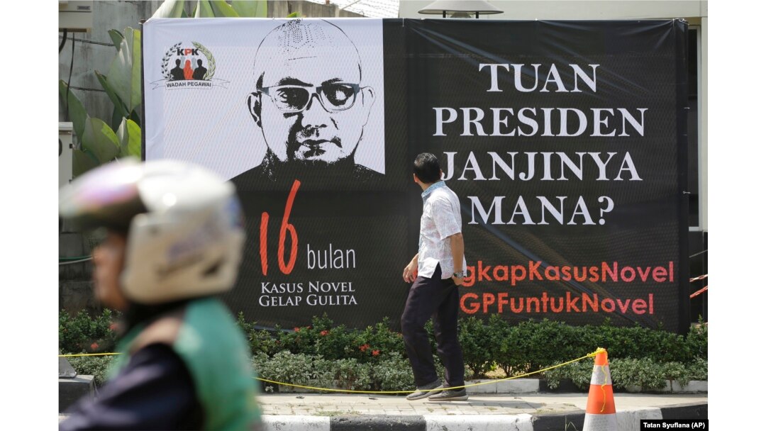 Seorang pria melihat poster di depan kantor KPK menyambut kembalinya penyidik Novel Baswedan, 27 Agustus 2018. (Foto: AP)