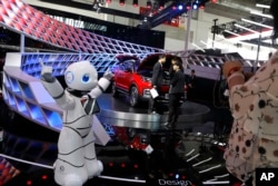 FILE - A robot entertains visitors at the booth of a Chinese automaker during the China Auto 2018 show in Beijing, China, April 26, 2018.