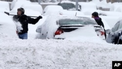 Workers at a Bloomington, Minnesota auto dealership remove snow left by a storm crawling east from the Dakotas and Minnesota toward Chicago that could bring up to 10 inches of snow in some areas, March 5, 2013.