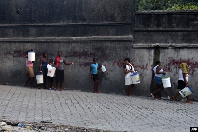 A group of women and children walk to buy water in the neighborhood of Petion Ville, in the Haitian Capital Port-au-Prince, on Feb. 14, 2019.