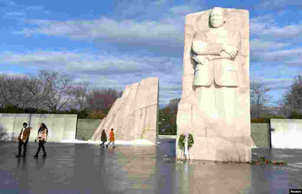 Visitors walk past the Martin Luther King, Jr. Memorial as the sun breaks through clouds after a stormy night, in Washington.