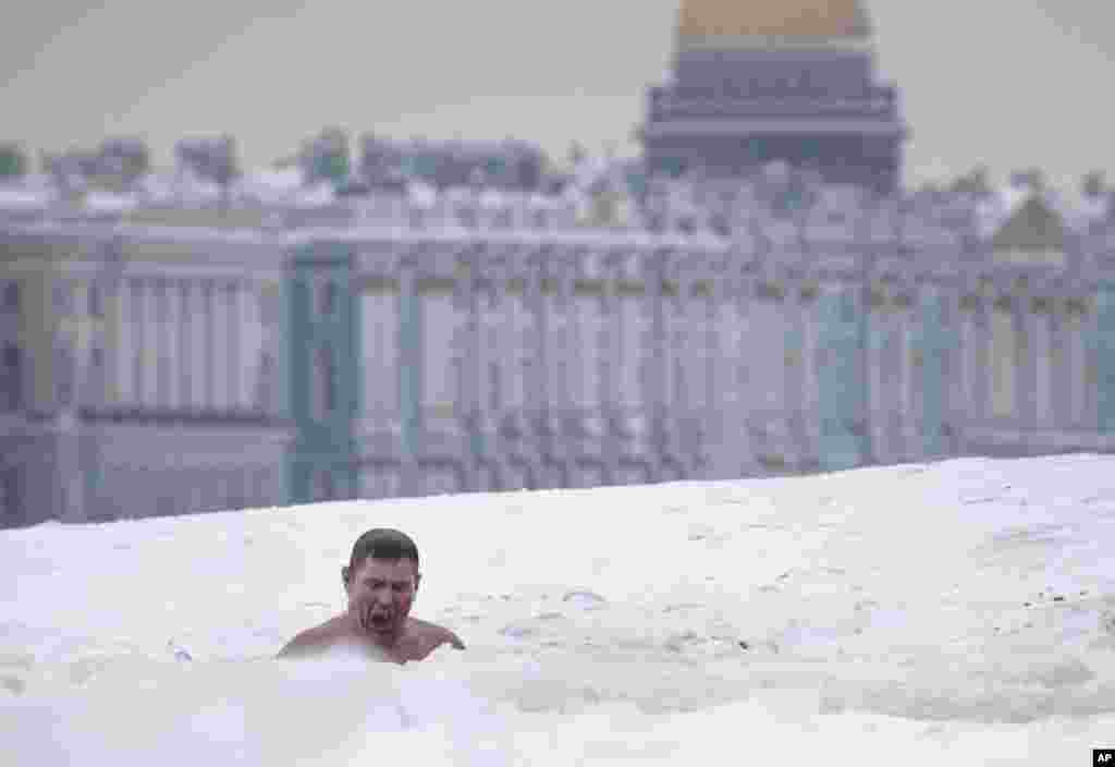 Seorang pria berenang di sungai Neva yang tertutup es di St. Petersburg, Rusia.