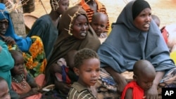 FILE - Somali women and children sit under a tree at a refugee camp in Dolo, Somalia while waiting for food rations.