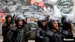 Riot police walk in front of graffiti depicting Bassem Mohsen, 20, who was killed in the 2011 Egypt uprising, along Mohamed Mahmoud street during the third anniversary of violent and deadly clashes near Tahrir Square in Cairo, Nov. 19, 2014.