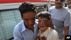 ایک ہزارہ شخص روتے ہوئے بچے کو سہلاتے ہوئے۔ منی بس میں سوار بچے کے خاندان کو مسلح افراد نے فائرنگ کر کے ہلاک کر دیا تھا۔ (2014)