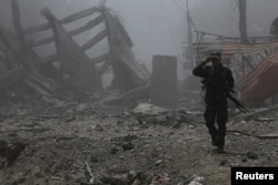 FILE - A member of the Iraqi federal police walks along buildings destroyed during clashes in the Old City of Mosul, Iraq, July 10, 2017.