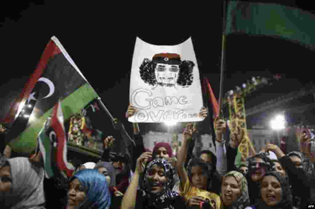 Women celebrate the revolution against Moammar Gadhafi's regime and ask for more women's rights, as they hols a banner depicting Moammar Gadhafi, Tripoli, Libya, Friday, Sept. 2, 2011. Rebel forces are advancing toward Moammar Gadhafi's hometown Sirte des