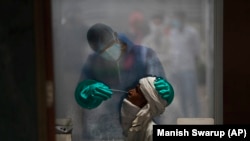 A health worker takes a nasal swab of a person for a COVID-19 test at a hospital in New Delhi, India, on July 6, 2020.