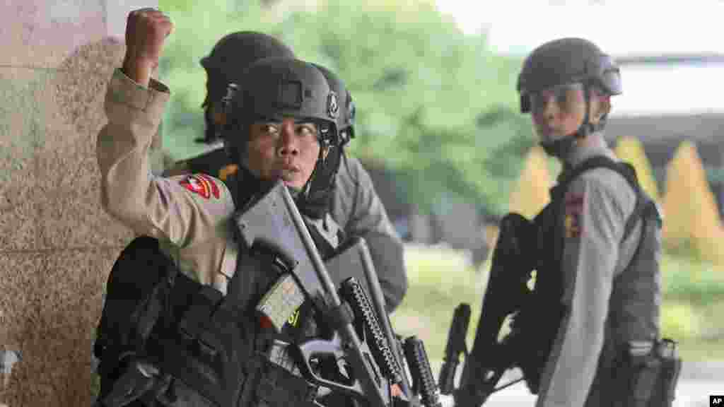 A police officer gives a hand signal to a squad mate as they search a building near the site of an explosion in Jakarta, Indonesia Thursday, Jan. 14, 2016. Attackers set off explosions at a Starbucks cafe in a bustling shopping area of downtown Jakarta and waged gun-battles with police Thursday, leaving bodies in the streets as office workers watched in terror from high-rise windows. 