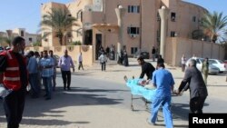 FILE - Rescuers transport a casualty, wounded during an airstrike on a food storage area, to Libya's Zawura Hospital, Dec. 2, 2014. 