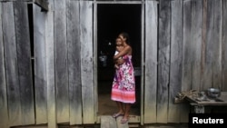 A woman holds her daughter outside their home in the Amazon rainforest near the city of Uruara, Para State, Brazil, April 20, 2013.