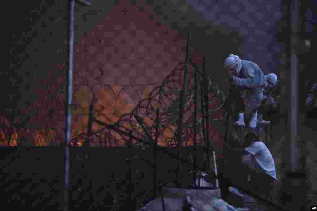 Para narapidana tampak berusaha lolos dengan melompati pagar saat terjadi kebakaran pada sebuah lapas di San Jose Pinula, Guatemala.