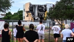 People watch as crews begin to demolish the building where seventeen people were killed during the 2018 mass shooting at Marjory Stoneman Douglas High School in Parkland, Florida, on June 14, 2024.