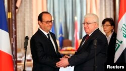 French President Francois Hollande shakes hands with Iraqi President Fuad Masum, right, during a news conference in Baghdad, Sept. 12, 2014. 