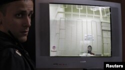 Леонид Развозжаев (на экране монитора) в зале суда