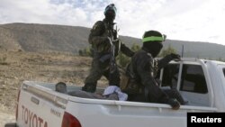 FILE - Fighters from the People's Protection Units (YPG), fighting alongside the Democratic Forces of Syria, ride on a pickup truck during what they said was an offensive against Islamic State militants to take control of Tishrin dam, south of Kobani, Syria Dec. 26, 2015.