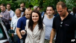 Sviatlana Tsikhanouskaya, candidate for the presidential elections, center, surrounded by her supporters walks after voting at a polling station in Minsk, Belarus, Aug. 9, 2020.