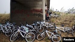 Syrian immigrants traveling by bicycle take shelter from the rain beneath a bridge near the Greek border with Macedonia, June 17, 2015.