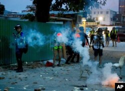 Journalists work near tear gas canisters deployed during a face-off between police and protesters at the Yuen Long district in Hong Kong on Saturday, July 27, 2019.